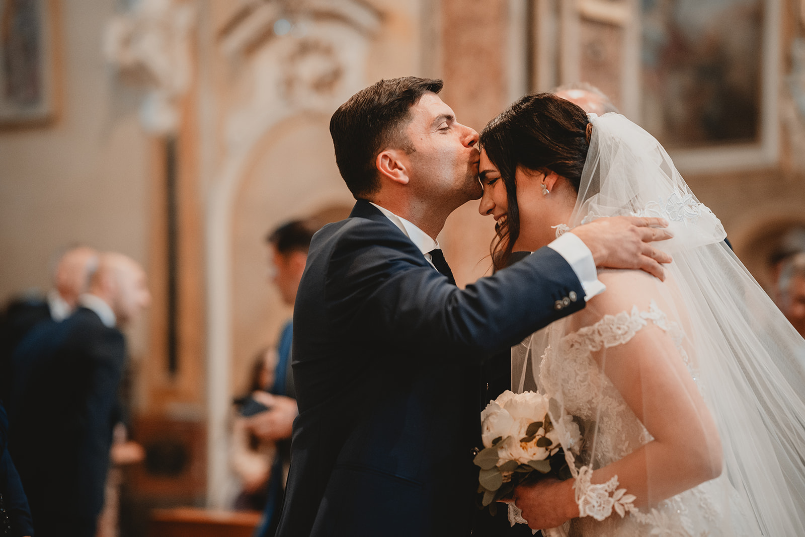 Sposo bacia in fronte la sposa all'ingresso in chiesa