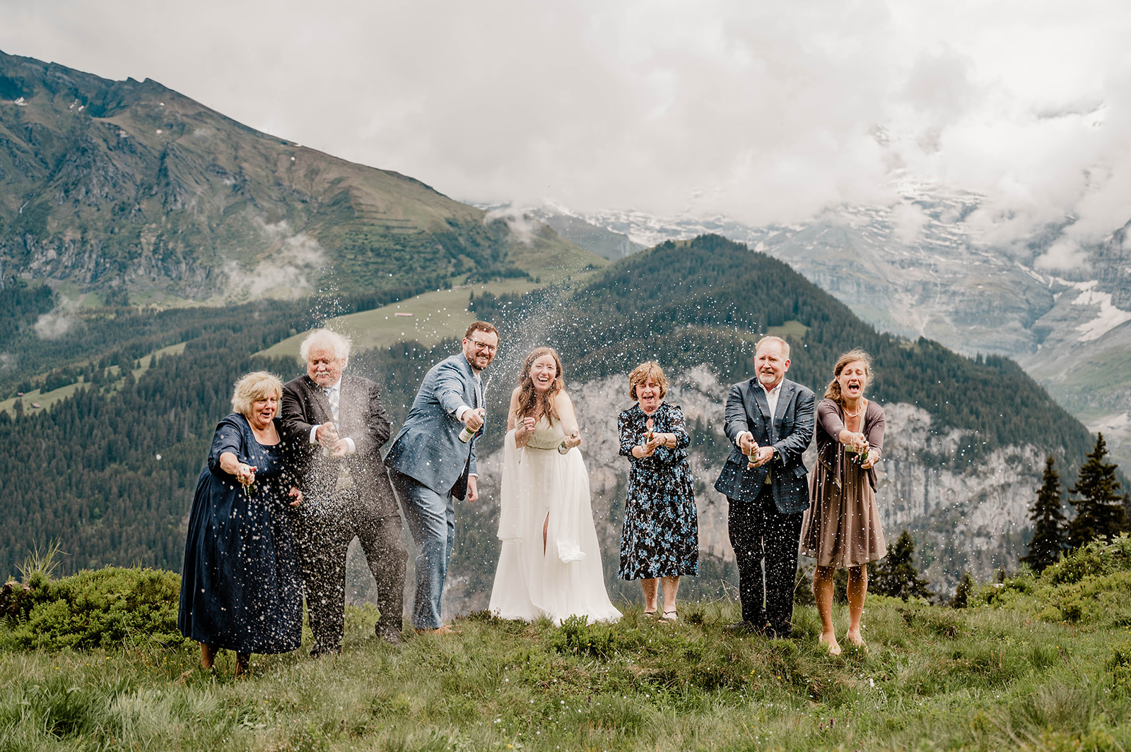 After an intimate elopement, family members and couple pop champagne above the Lauterbrunnen valley