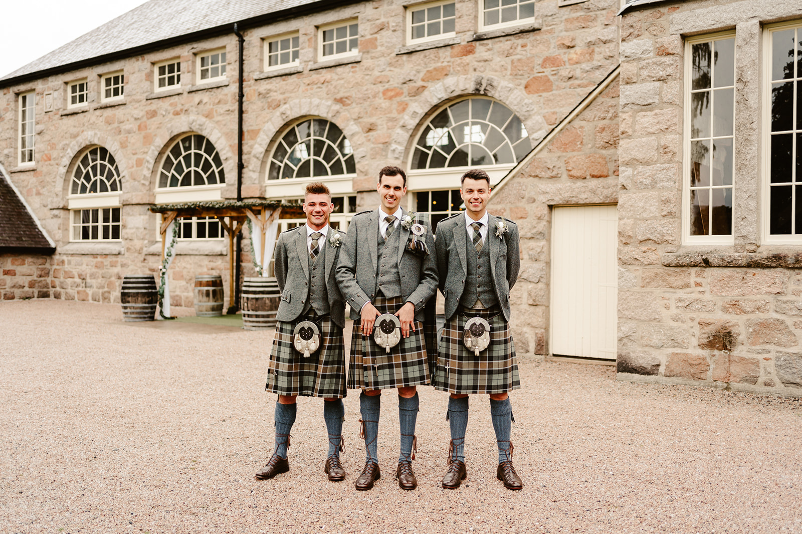 Image of three groomsman standing outside of The Coos Cathedral wearing kilts.