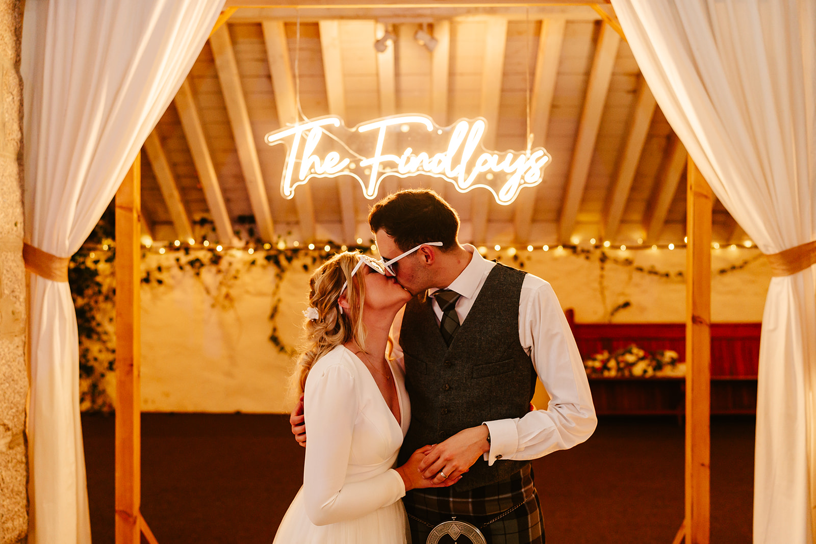 Couple standing under a neon sign for their wedding reception at The Coos Cathedral 