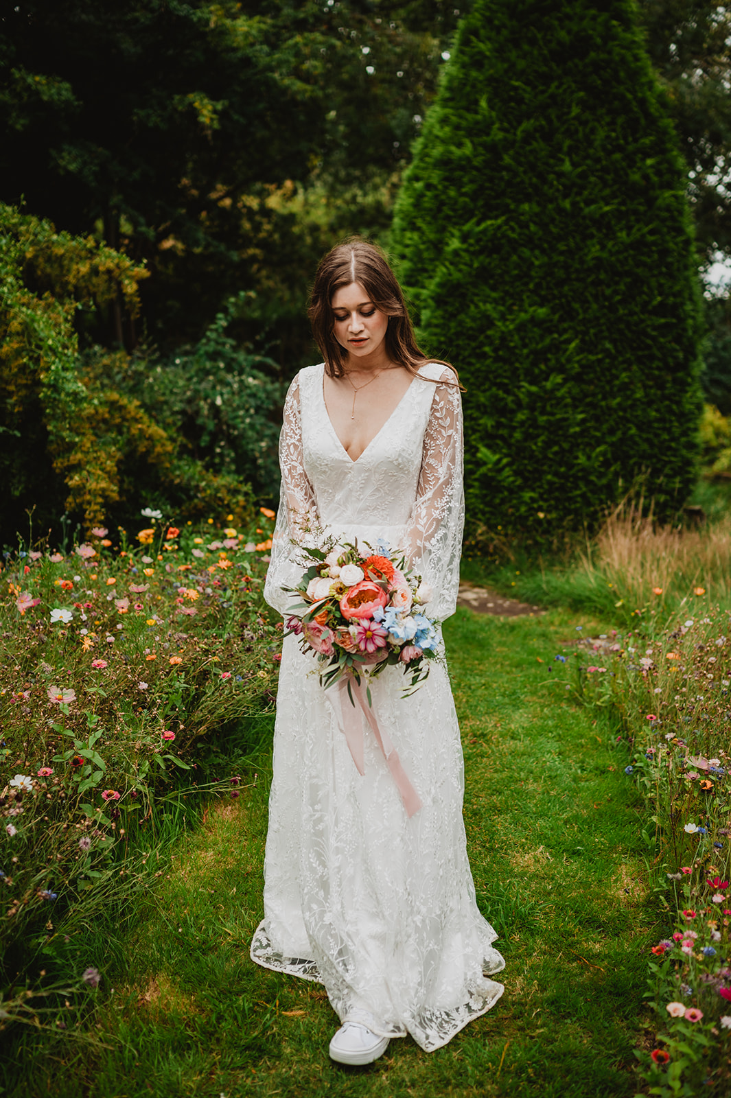 A bride poses with her flowers in the gardens at Redcoats Farmhouse