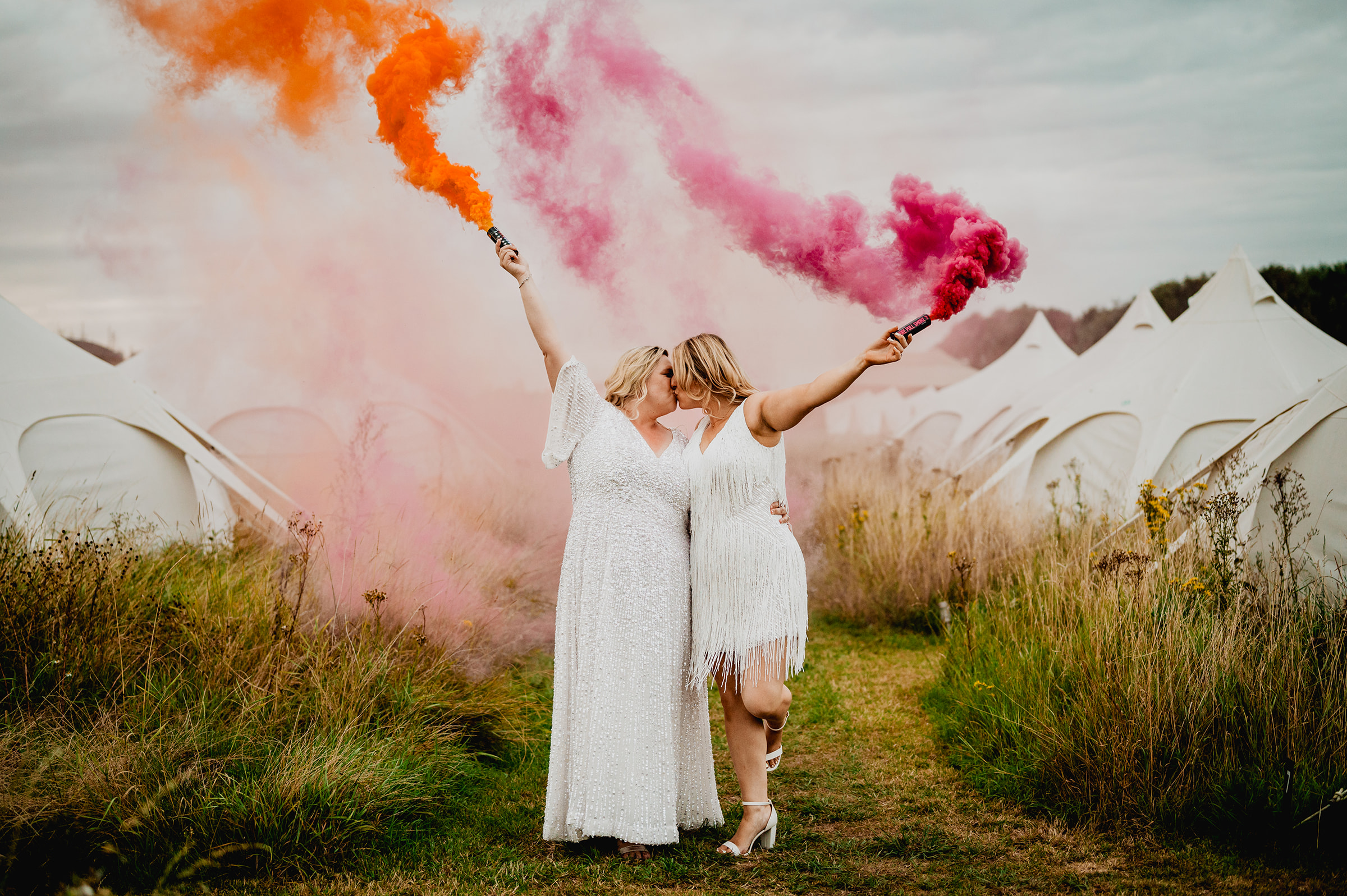 Same sex wedding with two brides holding smoke flares