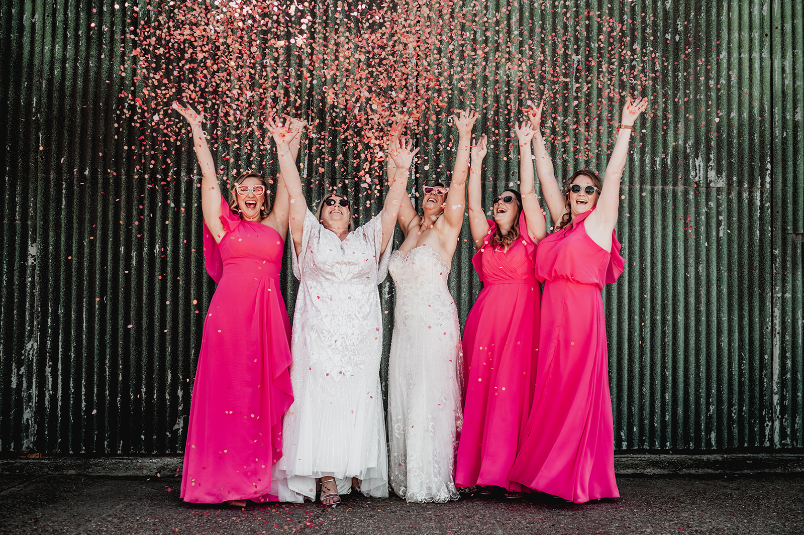 A bridal party celebrate by throwing confetti in the air