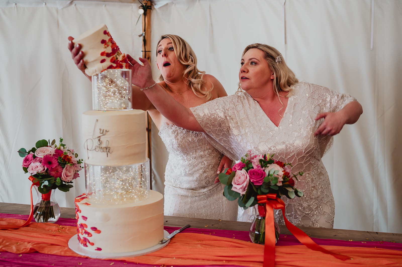 A just married same sex couple save their cake from toppling over during the cake cut