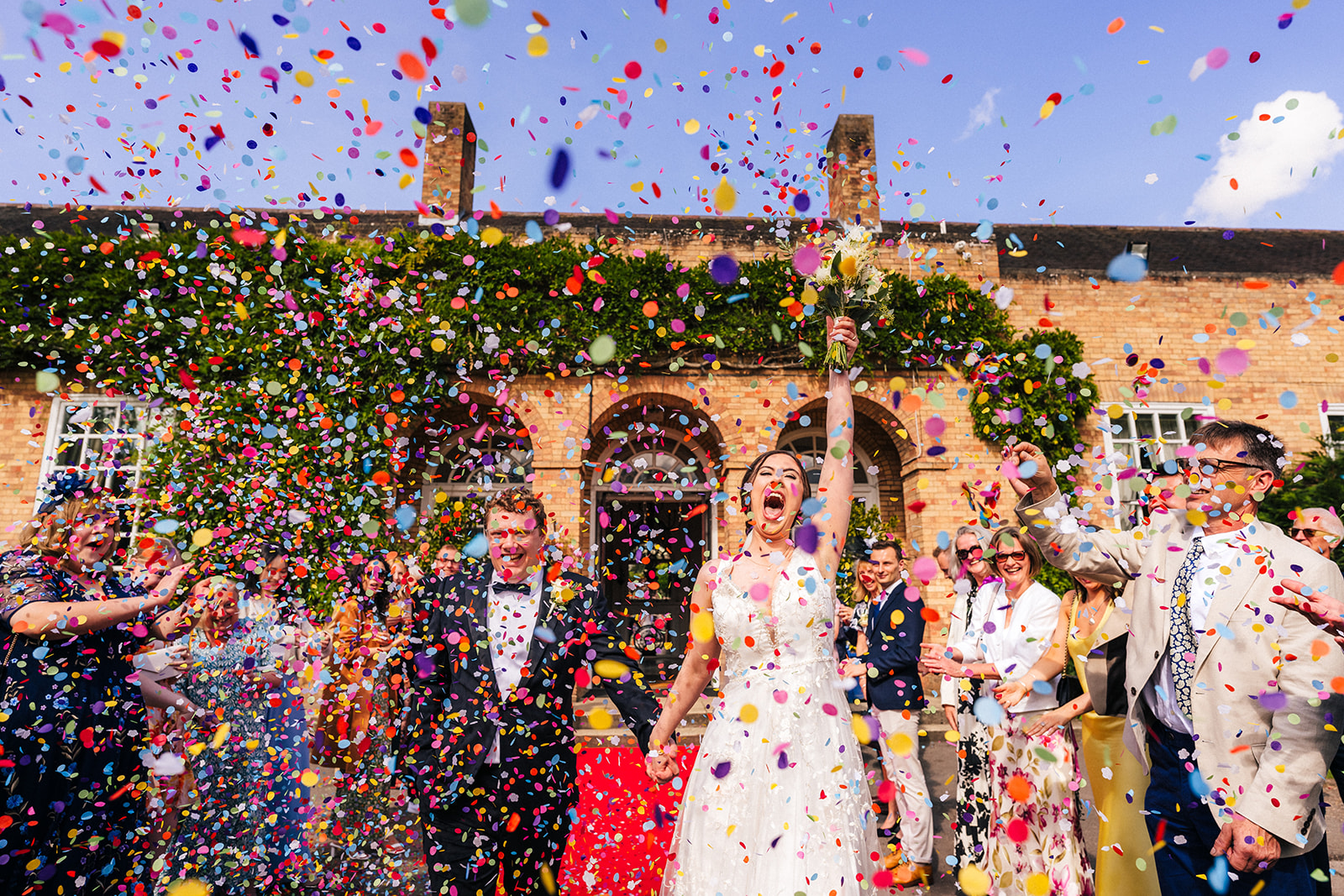 Hemswell Court Wedding Photography - bride and groom getting covered in confetti after their wedding ceremony
