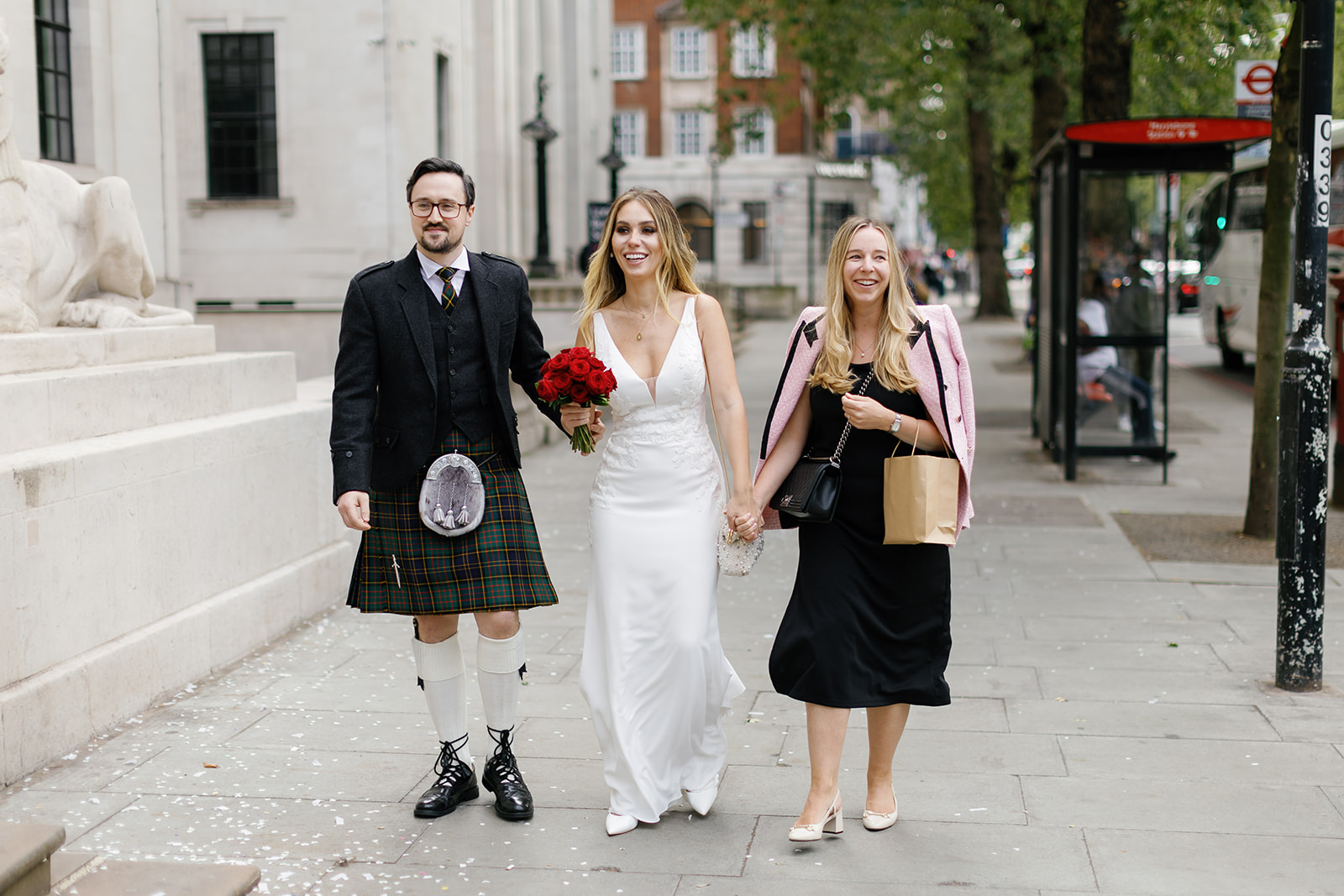 bride and groom with guest walking down the street