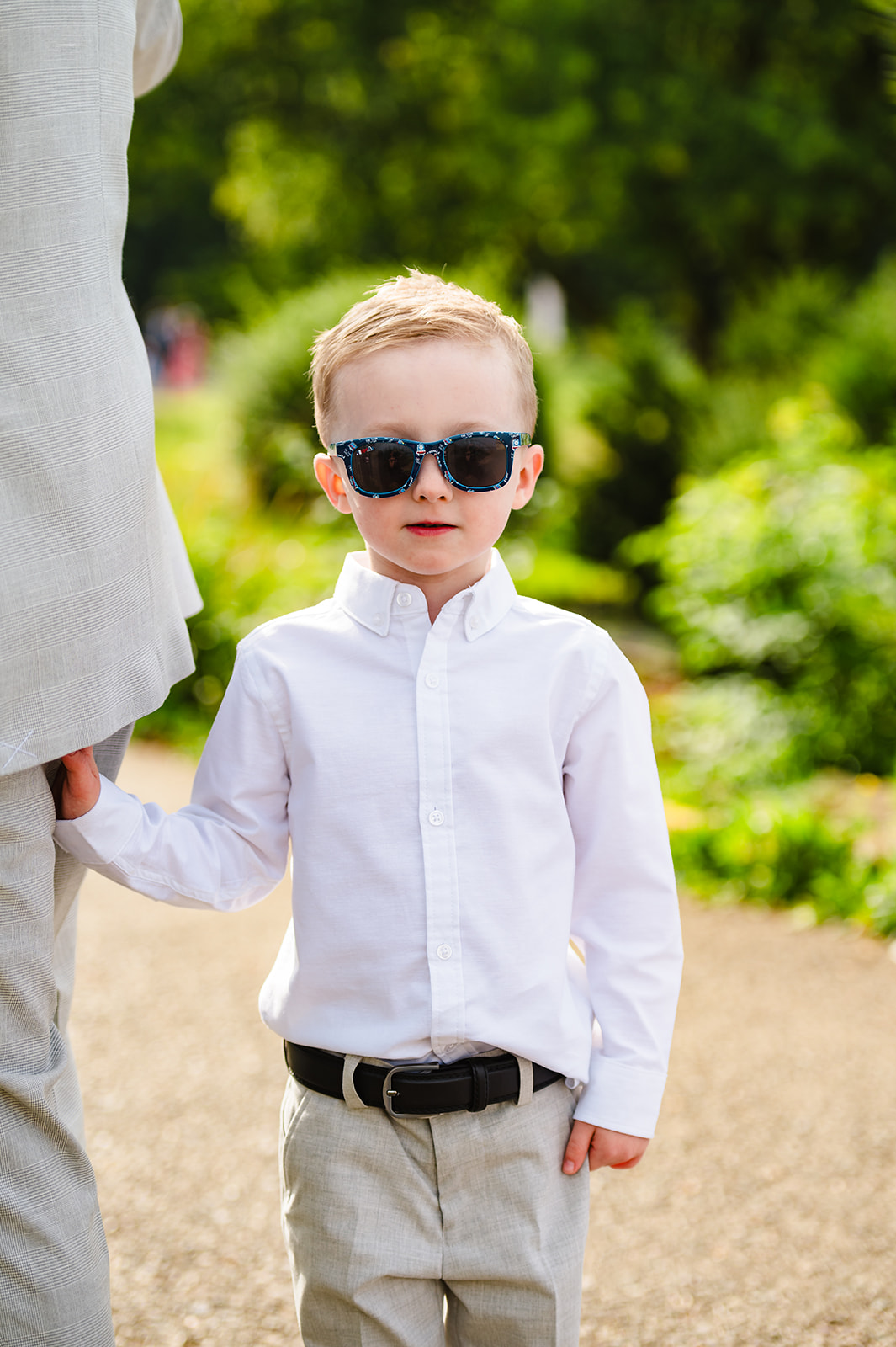 Boy wearing his wedding suit holding his dads hand before the wedding ceremony