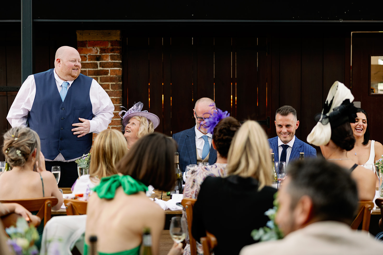 best man performing his wedding speech with guests laughing