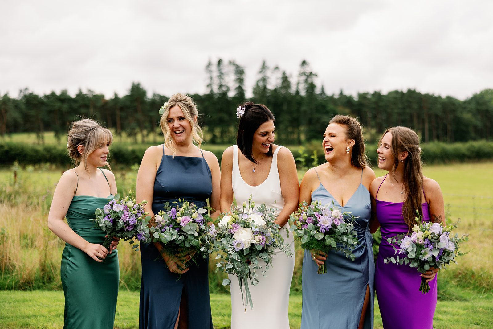 bride and bridesmaids laughing at each other whilst having their photo taken