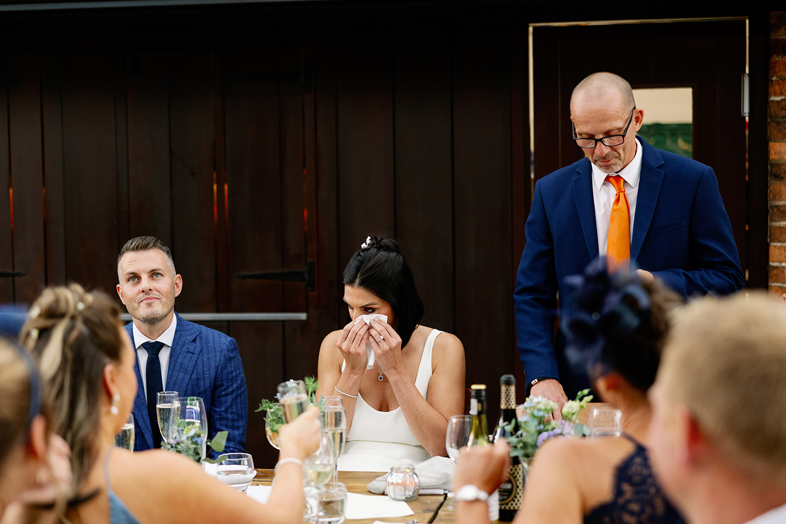 a bride getting emotional as her dad delivers his wedding speech