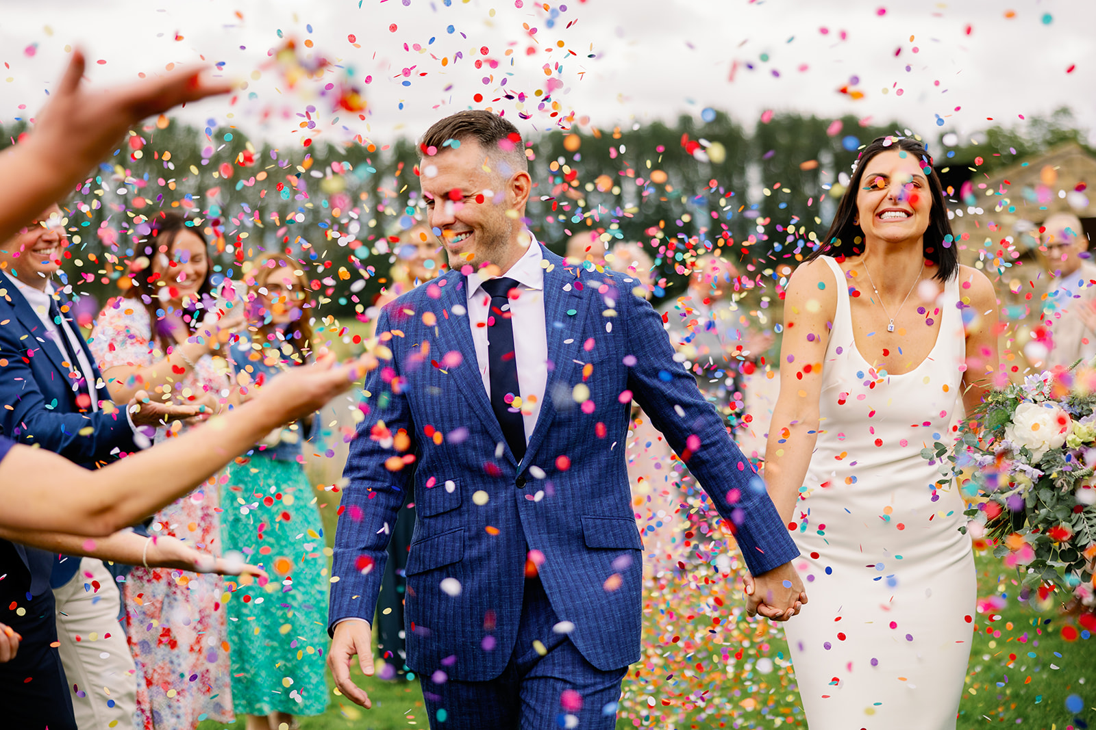 bride and groom having colourful confetti thrown at them at the hovels at harewood house