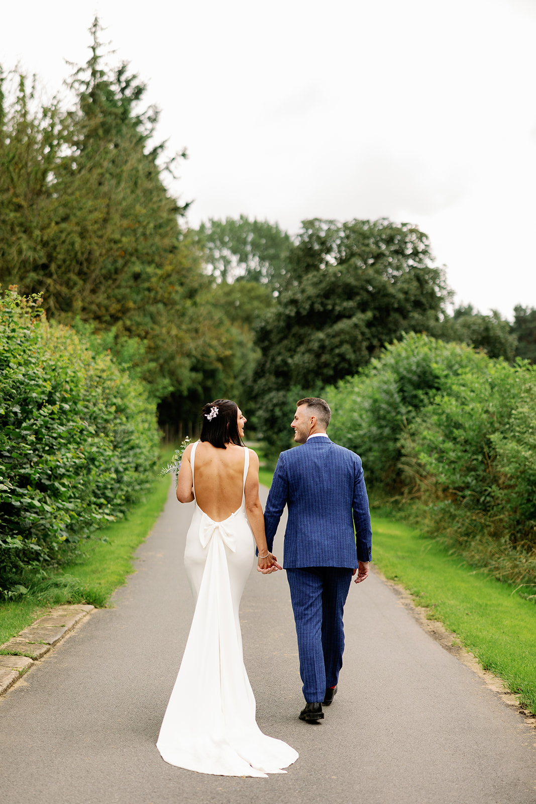 portrait of the bride and groom walking down a country lane