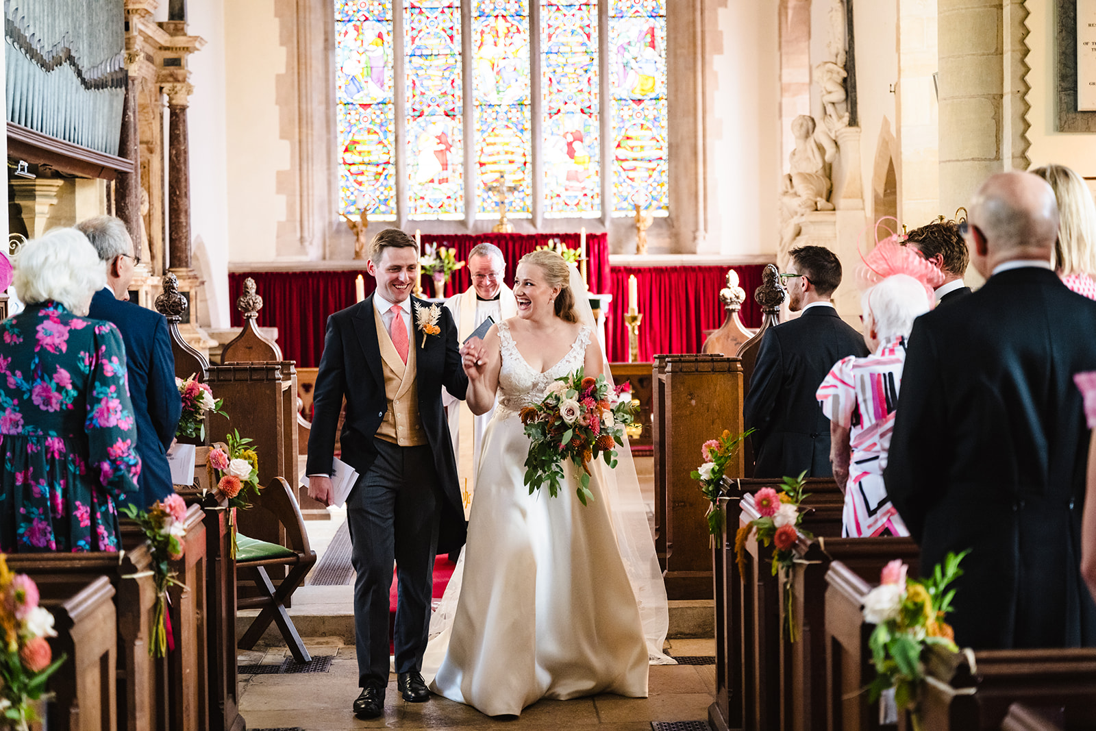 bride and groom walking back down the aisle as a newly married couple at st peter and st pauls church exton rutland