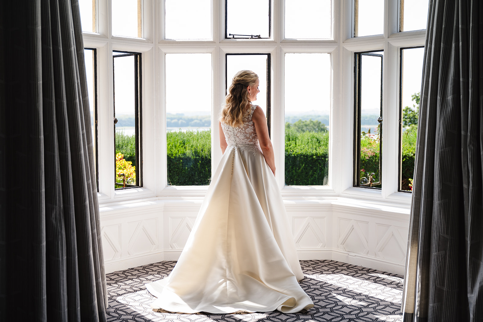 bride stands in the full length window in the bridal suite at rutland hall hotel