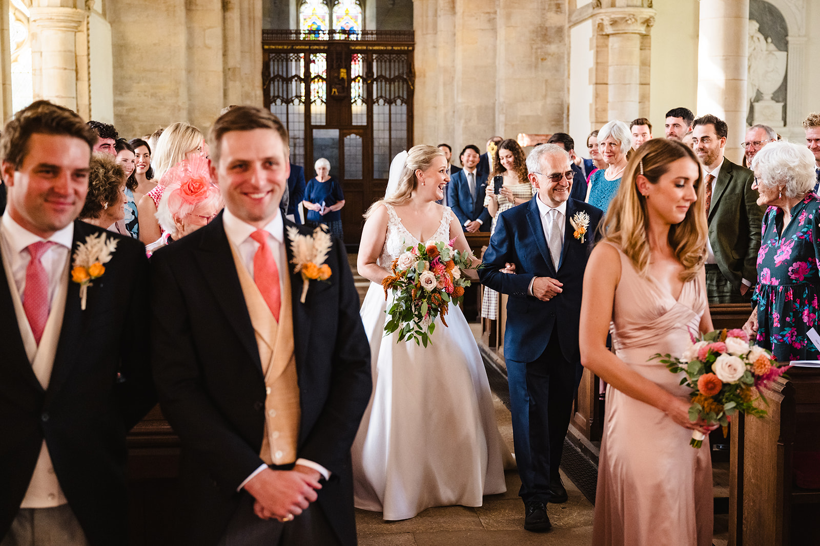 bride walks down the aisle to her groom at st peter and st pauls church exton rutland