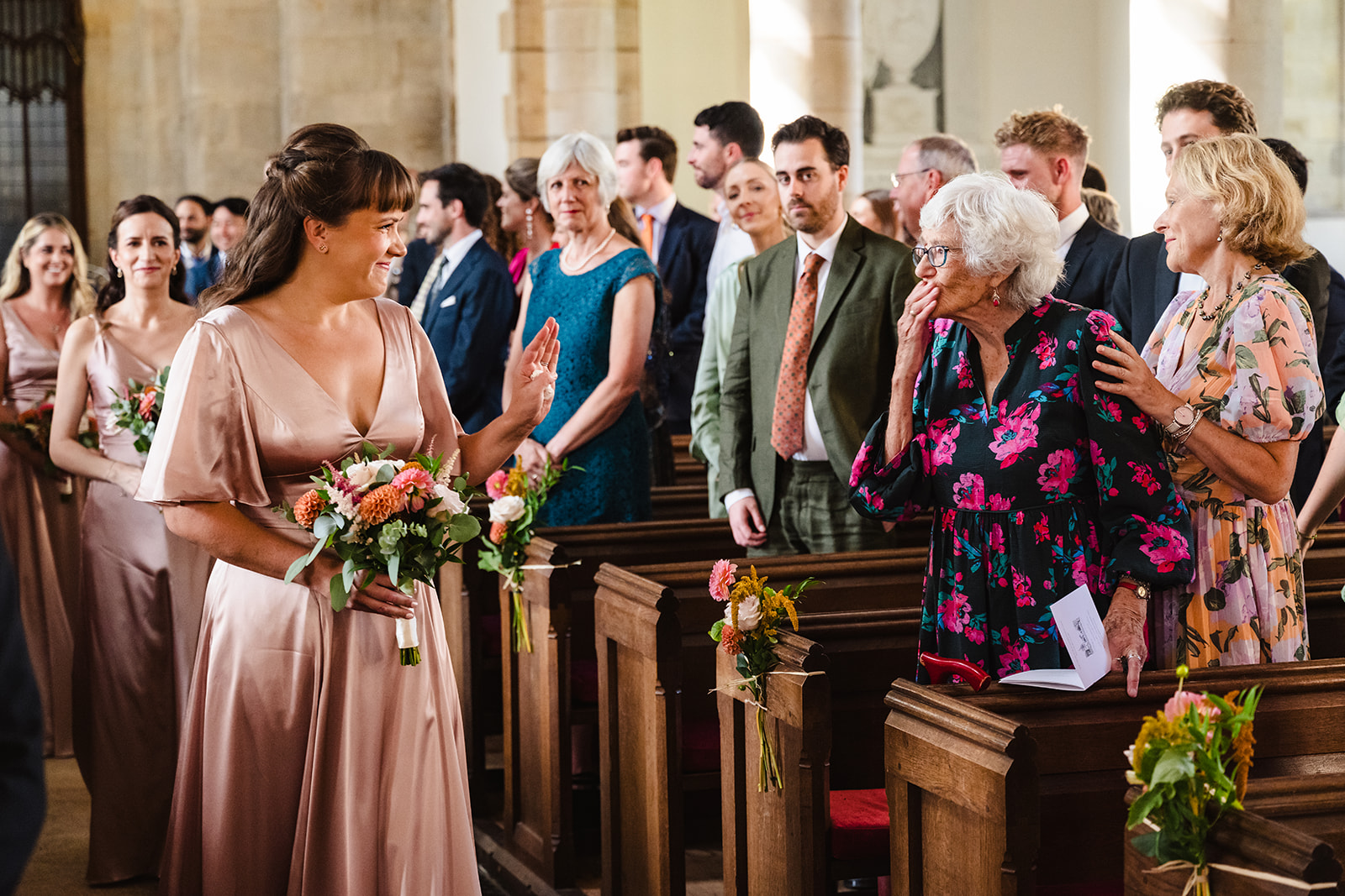 bridesmaid walks down the aisle at st peter and st pauls church in exton rutland