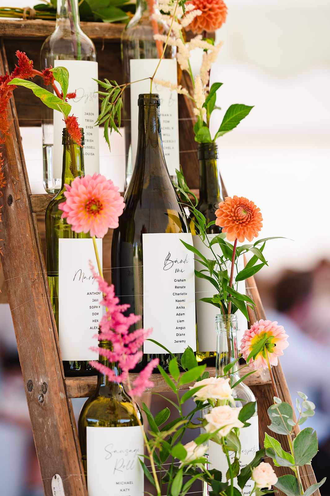 wine bottle table plan with flowers set on a ladder