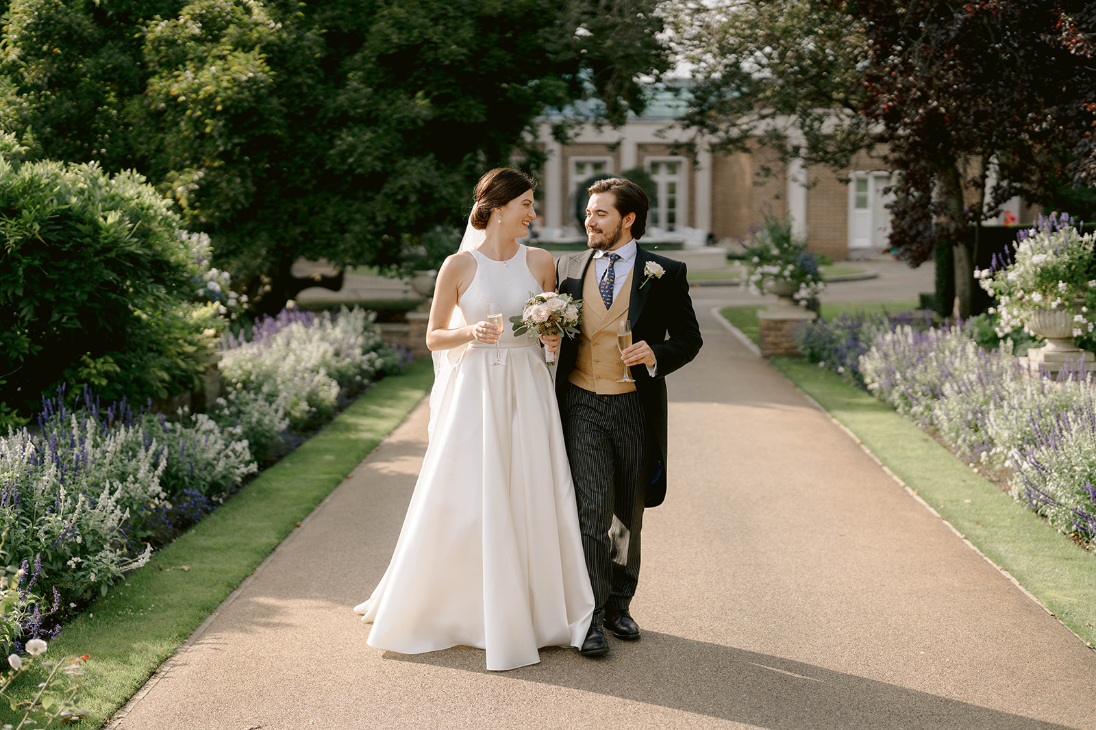 couple walking through the gardens in summer at the hurlingham club fulham