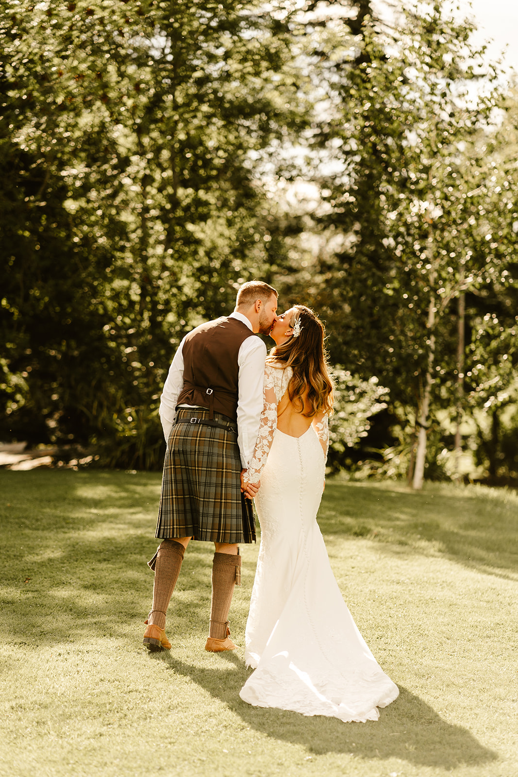 Couple kissing on the lush green lawn at Aswanley wedding venue