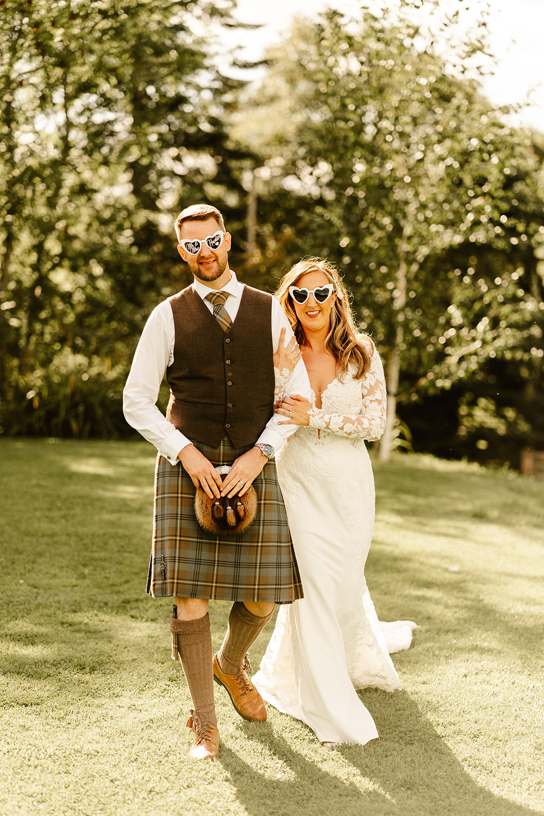 Couple wearing heart shape glasses on the lush green lawn at Aswanley wedding venue