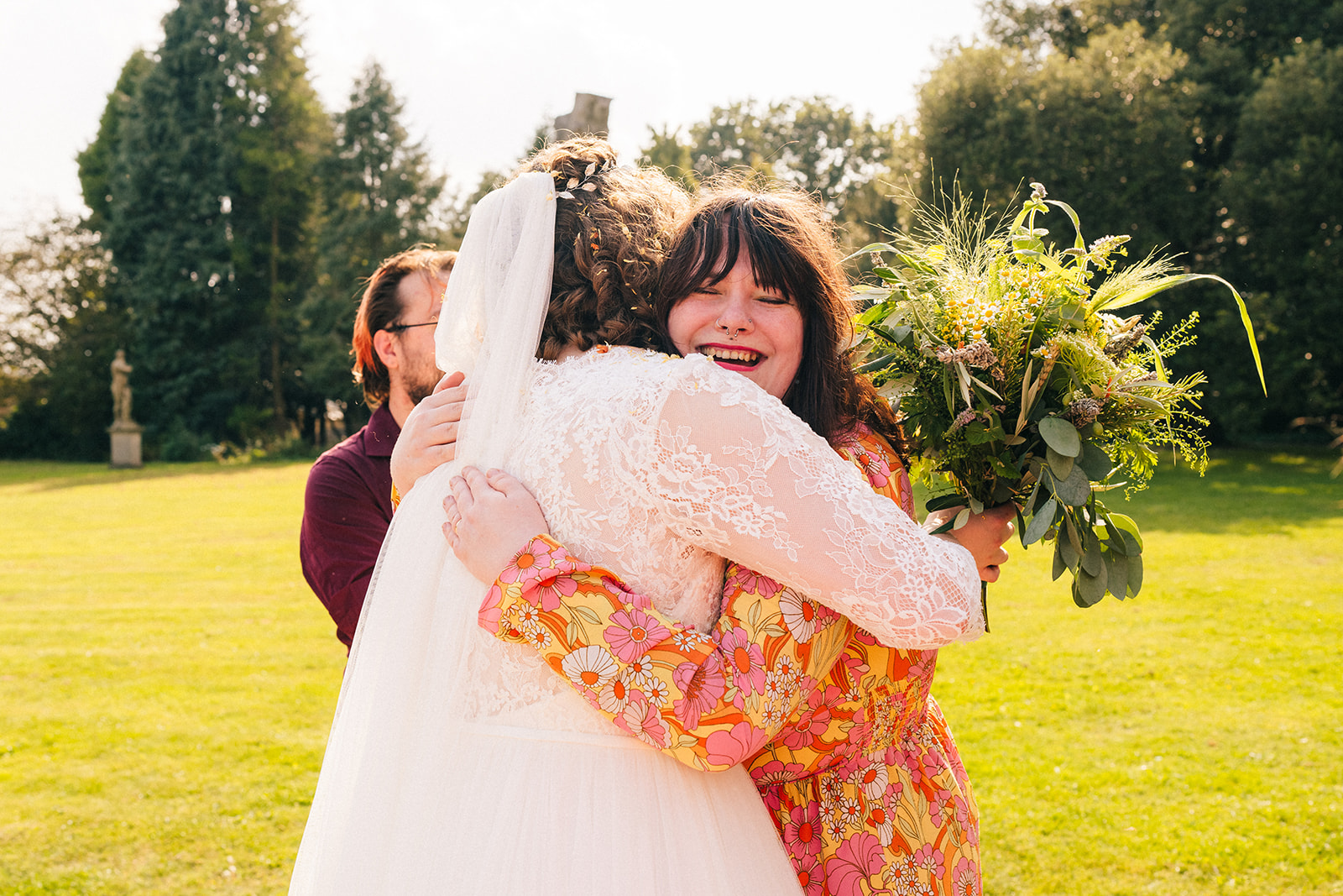 bride and a wedding guest hug at Wollaton hall