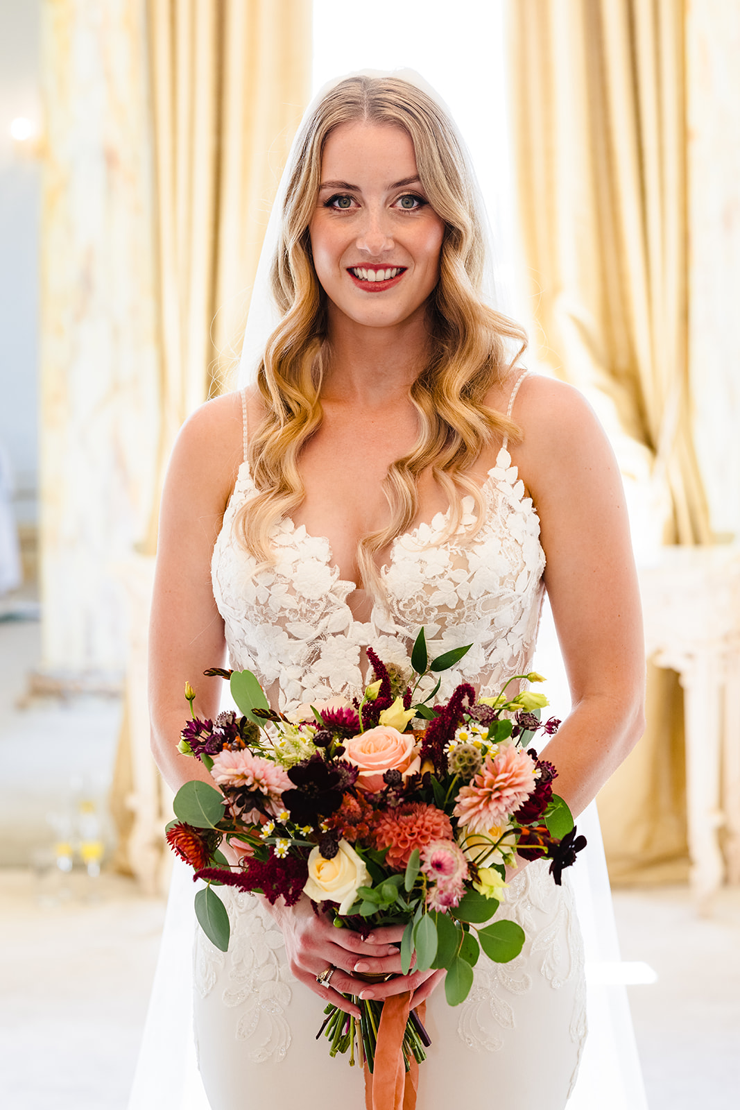 Bride standing with her bright wedding bouquet in rococo suit at gosfield hall