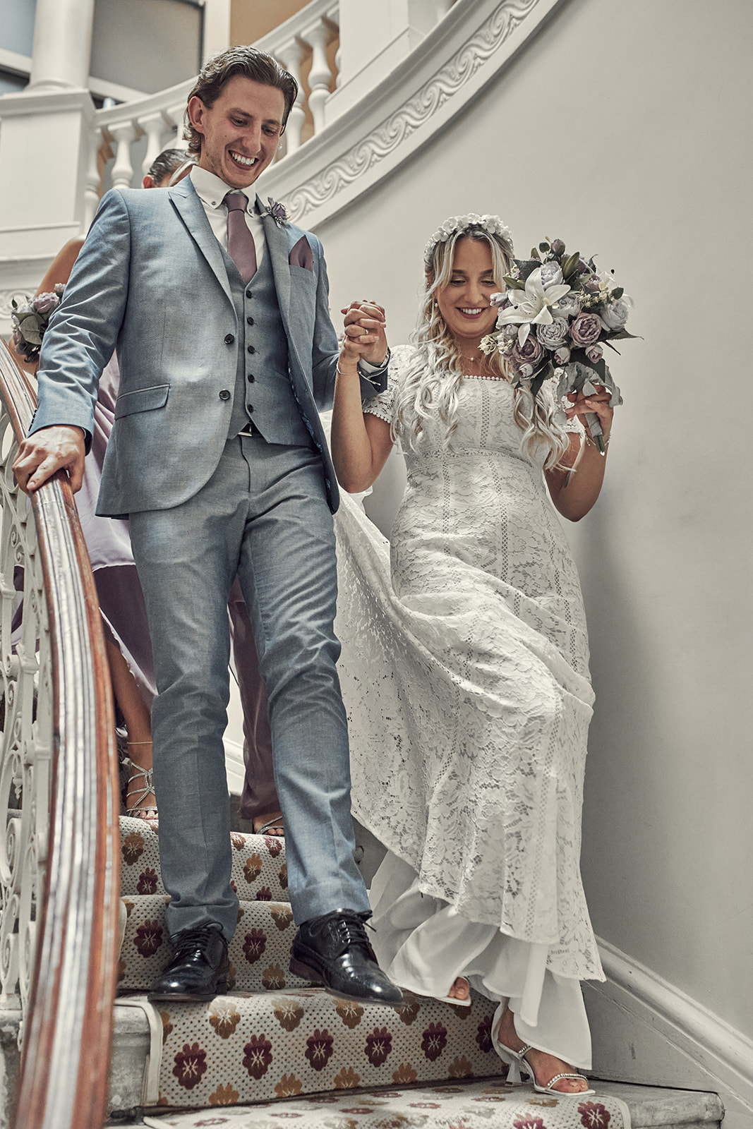 bride and groom hold hands while making their way out through stairs