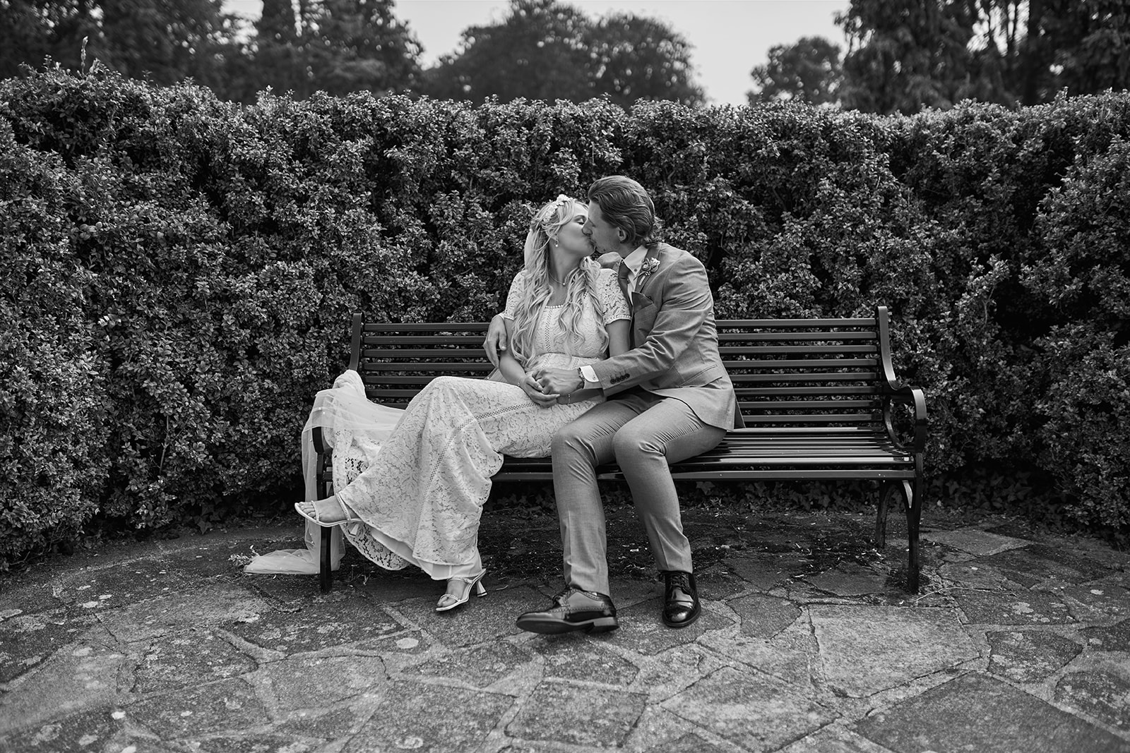 bride and groom kissing while sitting on the bench 