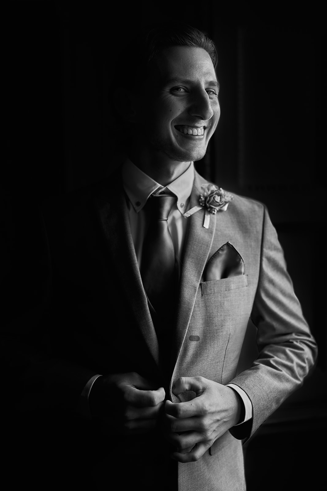 portrait of groom smiling and looking outside the window