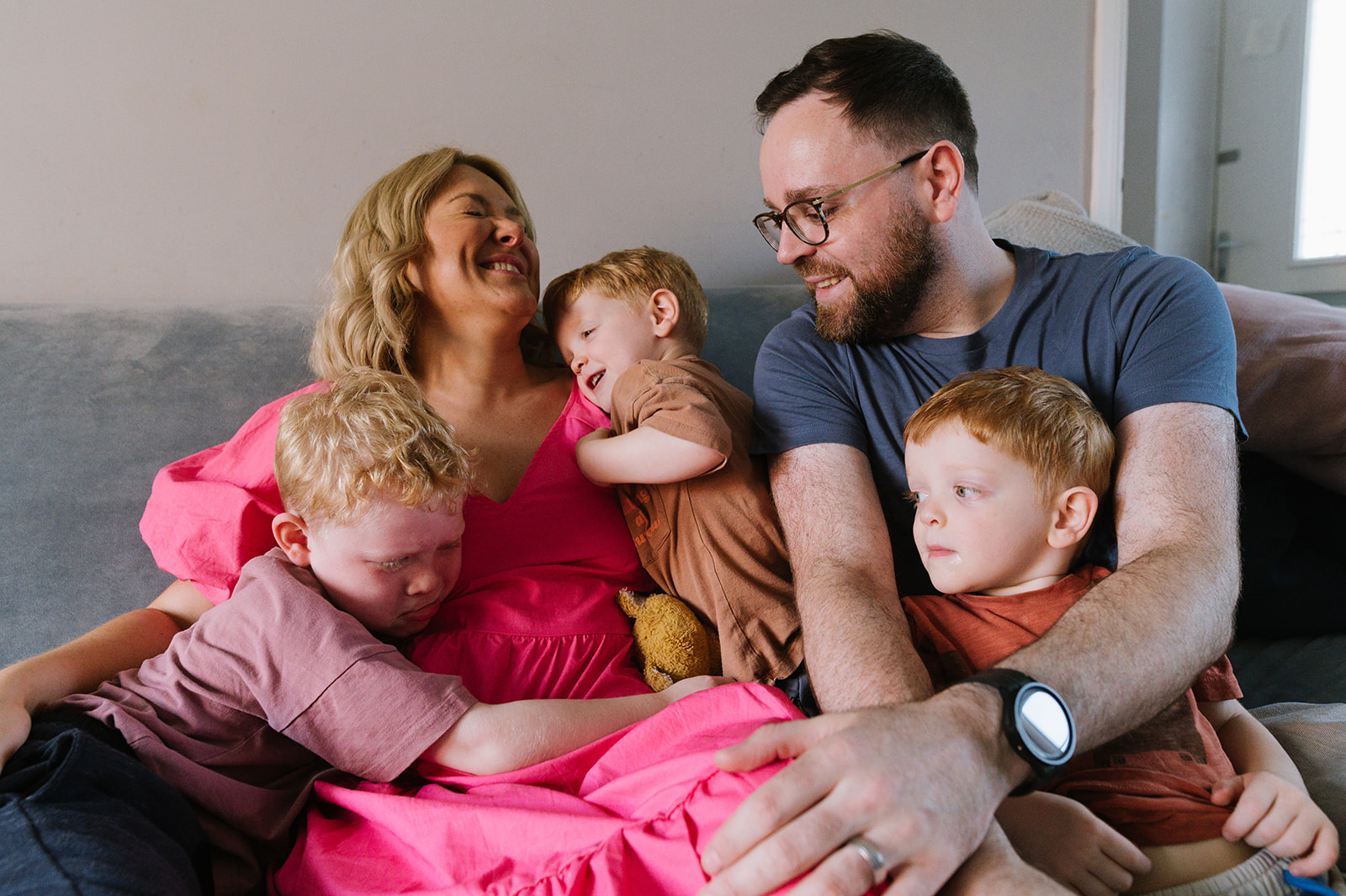 A family of 5 snuggle on the sofa for relaxed family photos at their home