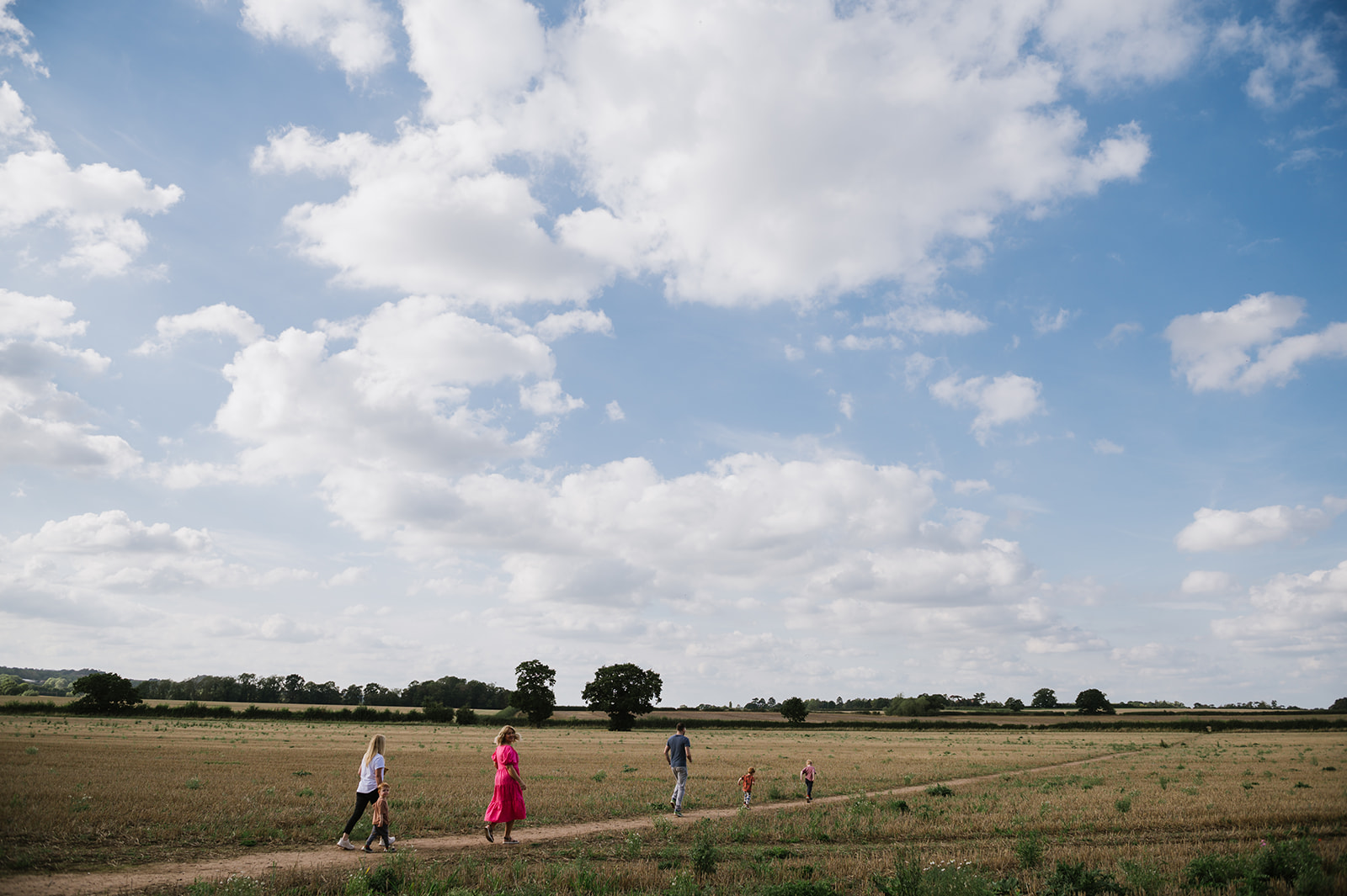 Family walking through fields in summertime for relaxed family photos