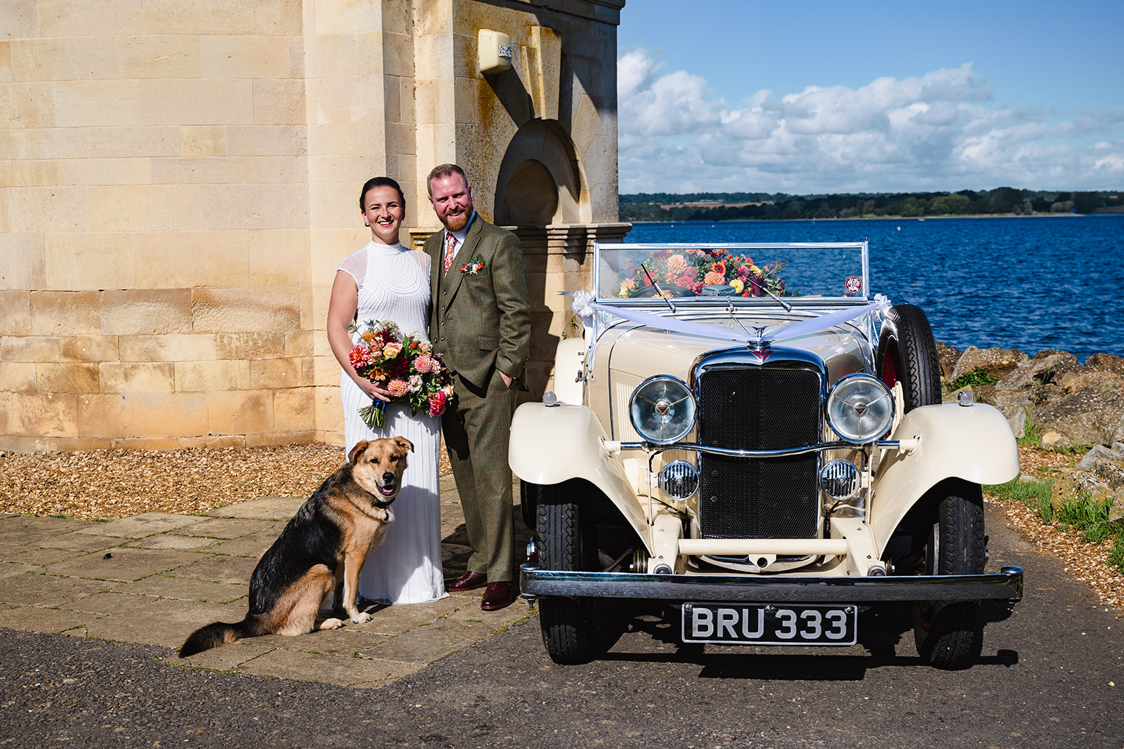 Bride and groom with their dog and wedding car at normanton church rutland water