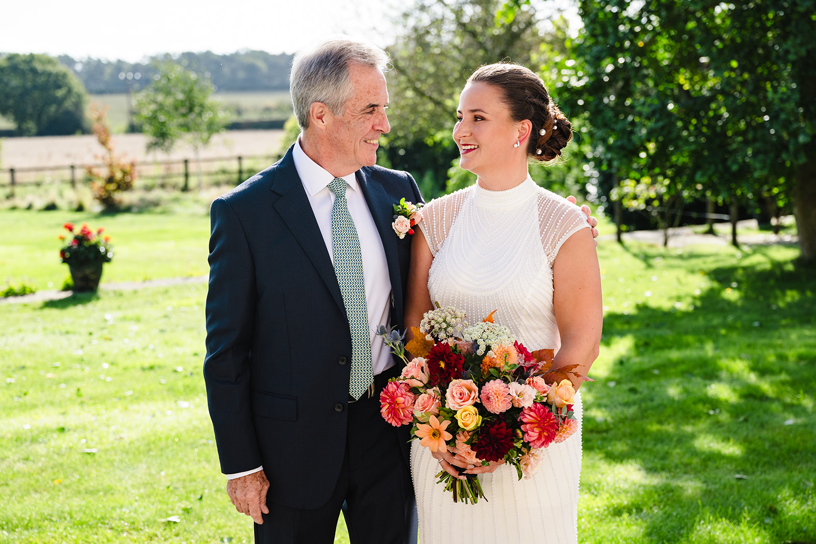 Bride and her father stood looking at each other in the garden