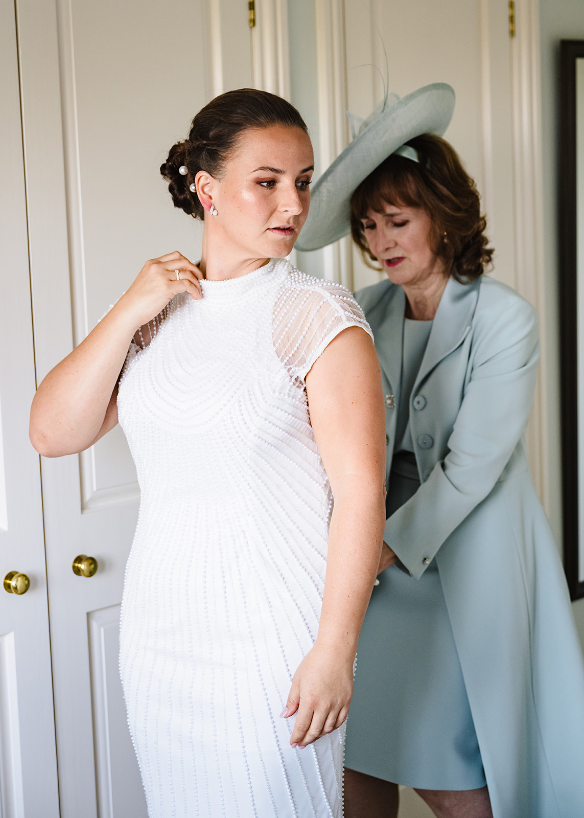 Brides mum helping her get in to her dress