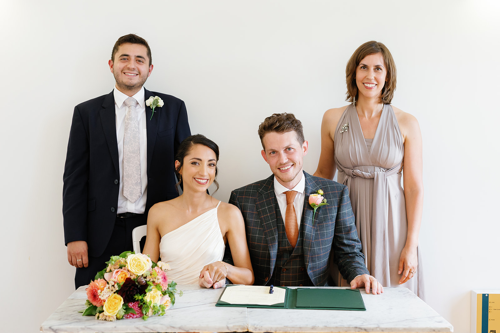 bride and groom signing marriage contract with siblings as witness
