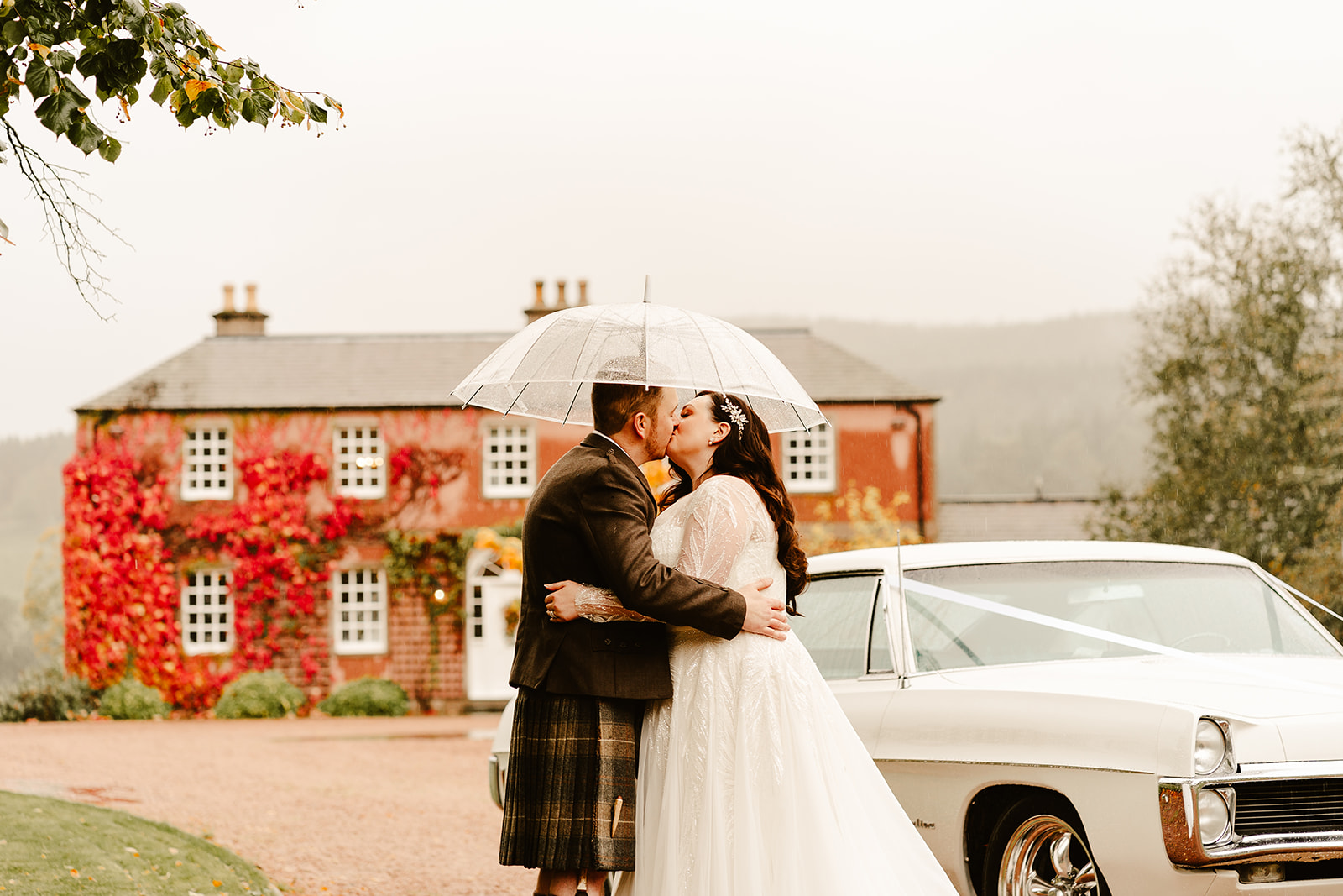 couple kiss in the rain in front of ballogie house scotland wedding