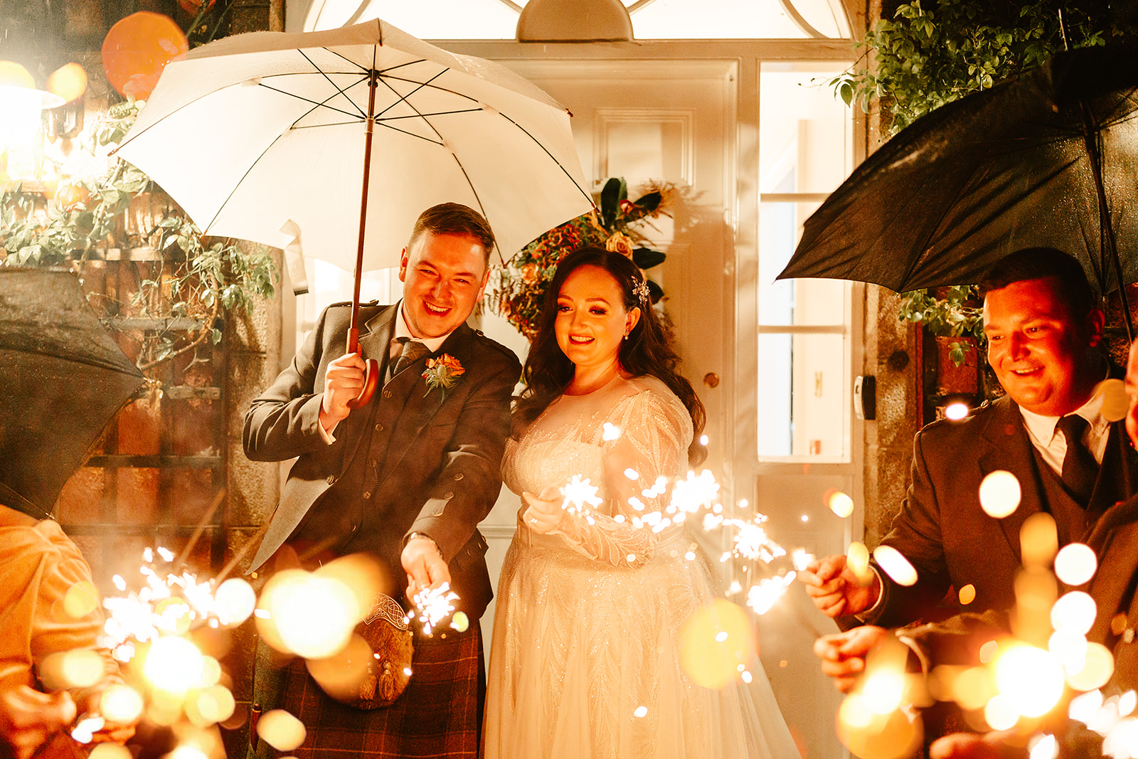 couple stand under an umbrella and holds sparklers in the dark at ballogie house