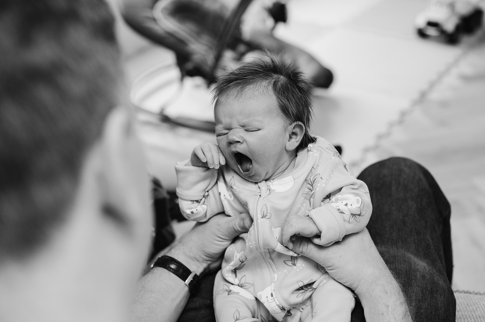 newborn yawning while lying on his dads lap