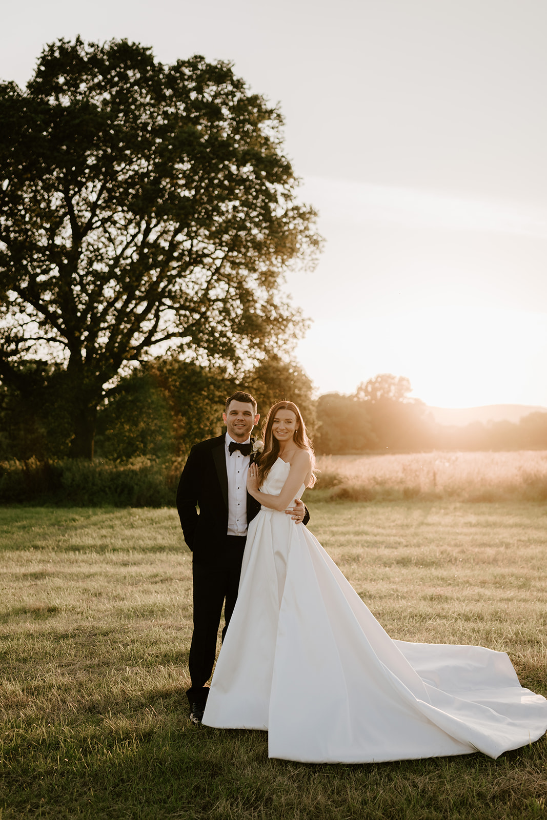 groom and bride in field with malvern hills at sunset 