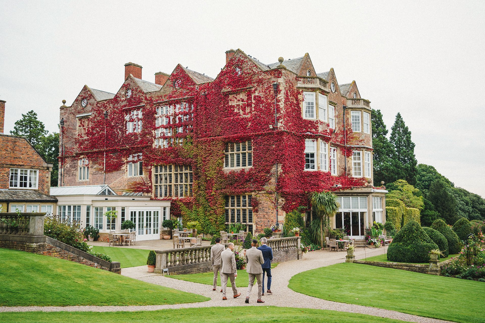 groom and ushers arriving at goldsborough hall, building covered in red ivy 
