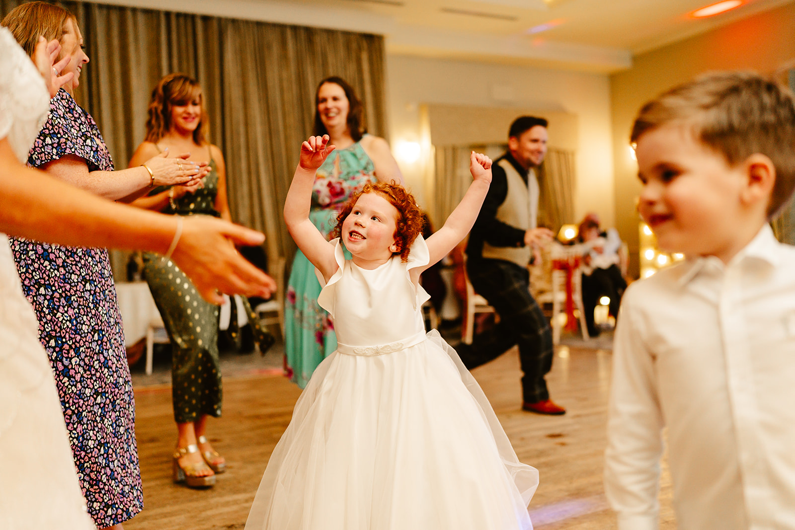 young girl throws hands in the air as she dances on dancefloor at maryculter house hotel wedding