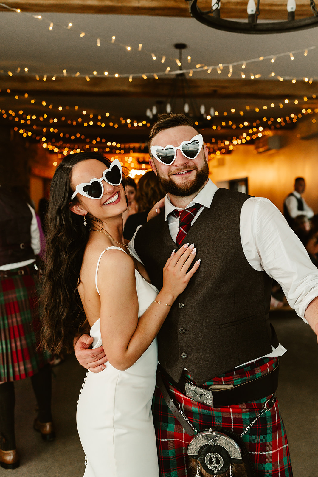 bride and groom pose together on dancefloor wearing heart shaped sunglasses at Schivas Steading wedding