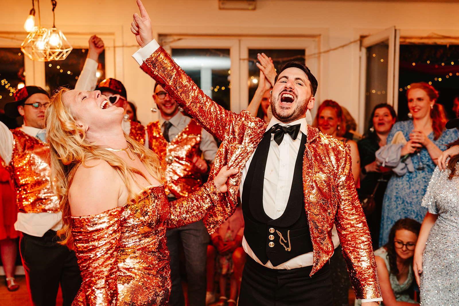 bride and groom dressed in gold sequin outfits signing on the dancefloor at Venachar Lochside wedding