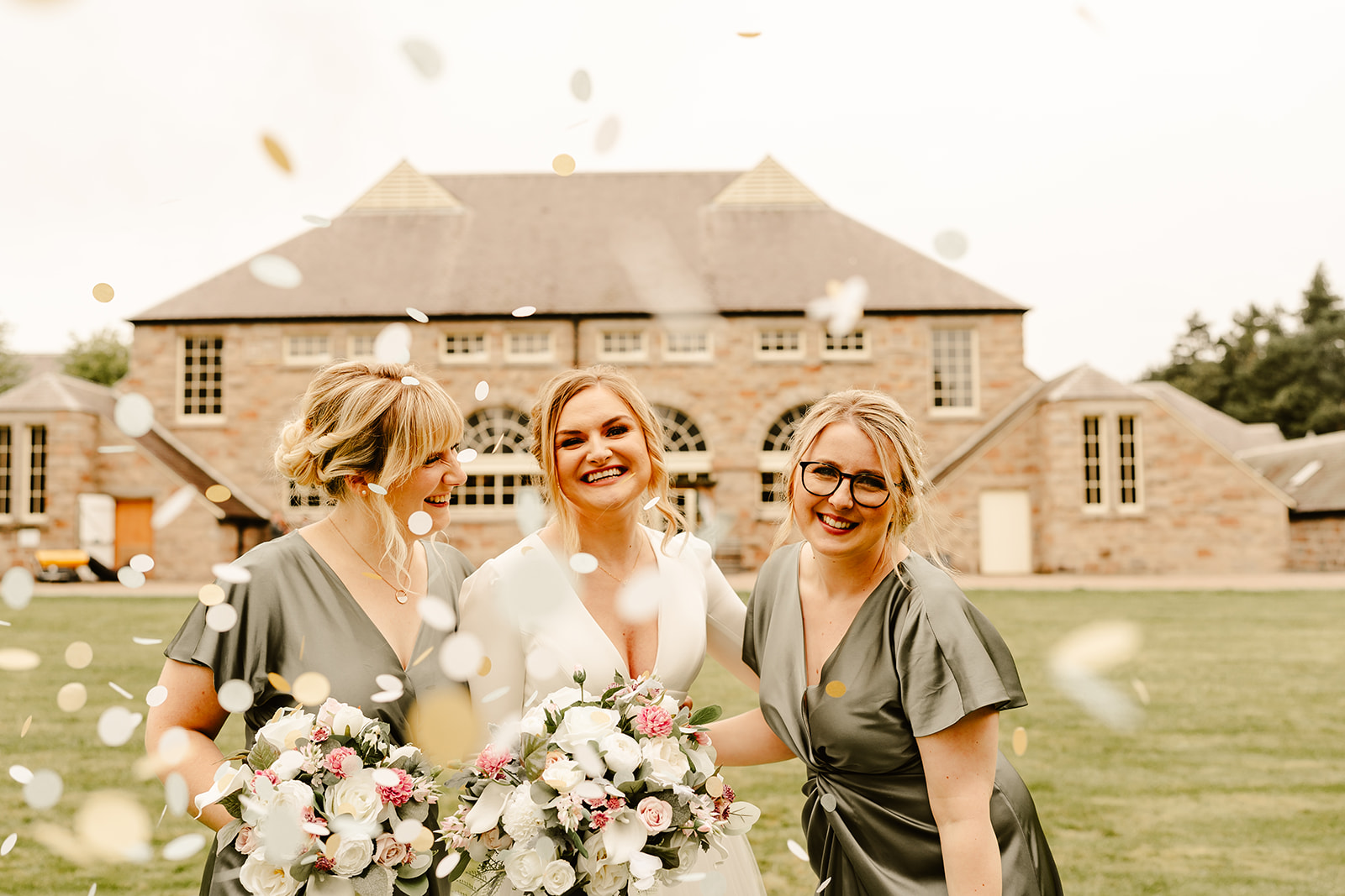 bride and two bridesmaids smile whilst confetti falls down on them inferno of coos cathedral wedding venue