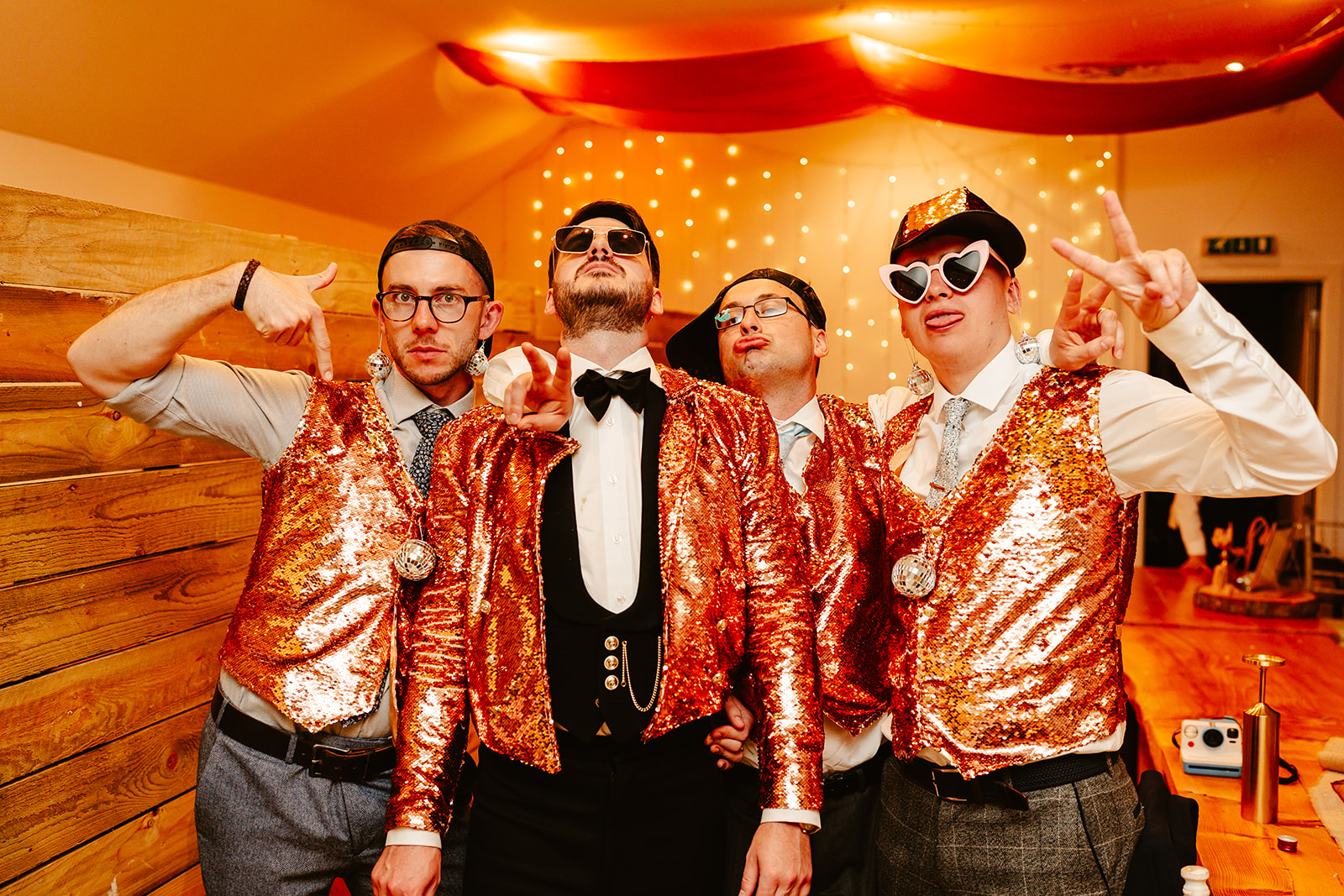 four men pose wearing gold sequin outfits inside Venachar Lochside wedding venue