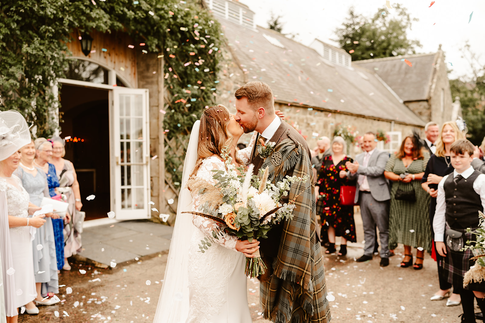 couple kiss outdoors during confetti throwing at Aswanley 