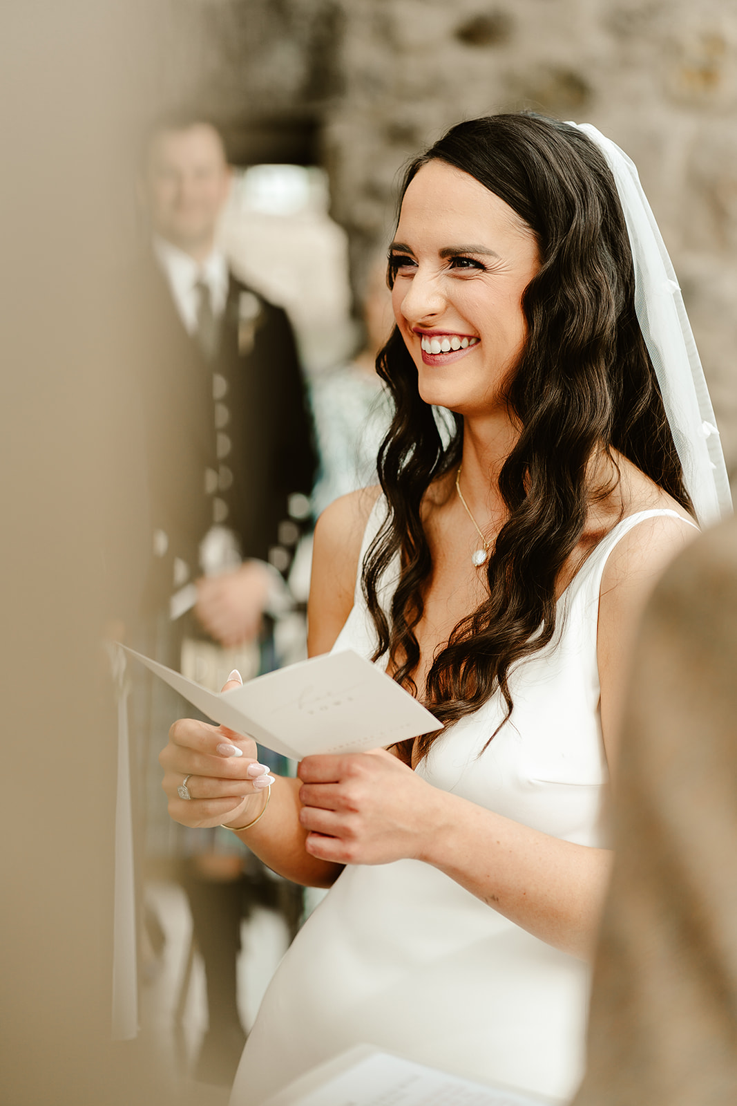 a bride looks at her groom whilst she reads her wedding vows 