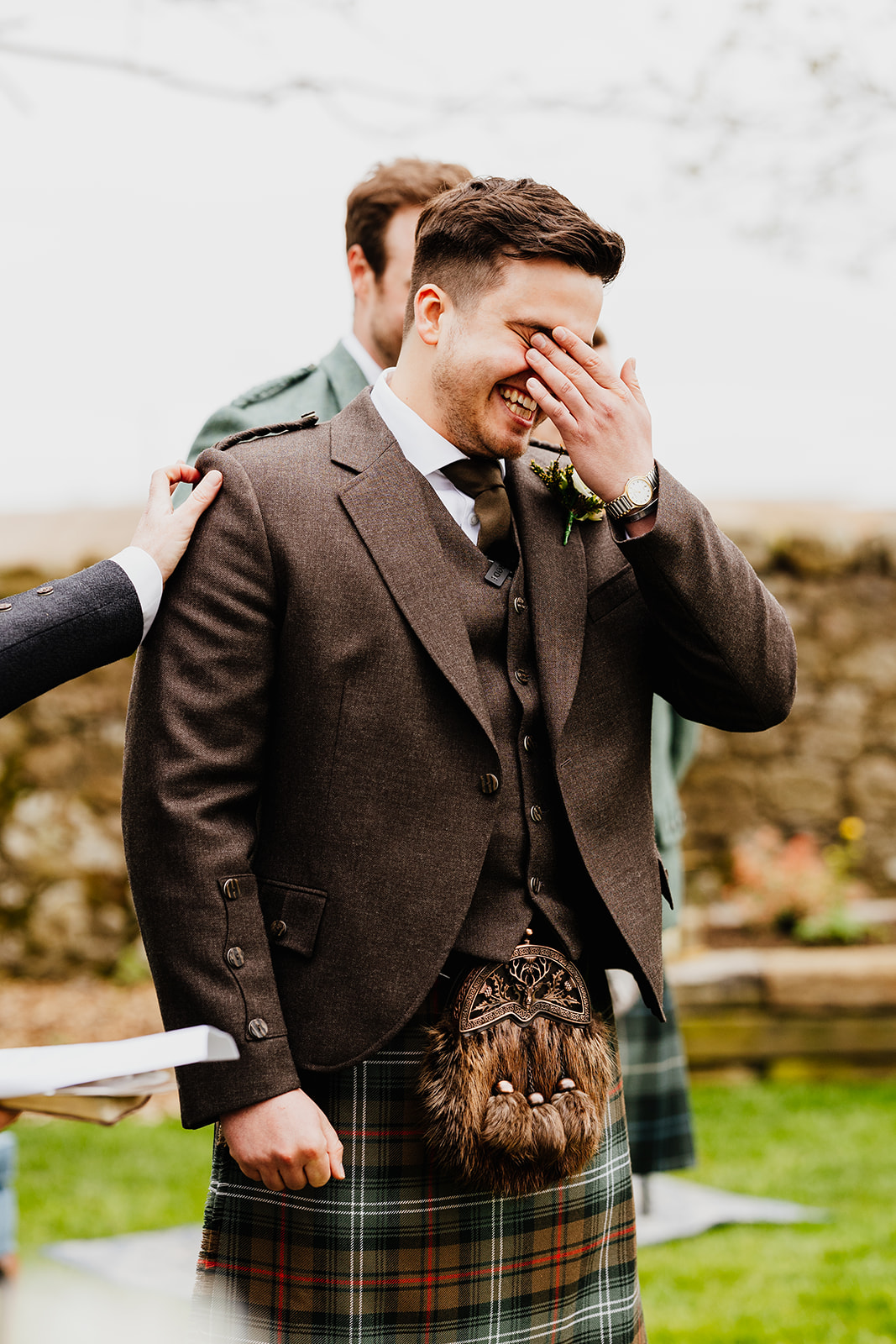 grooms cries into his hand as he watching his bride walk down the aisle