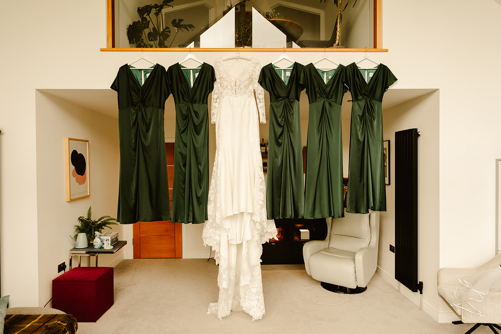 a wedding dress and five bridesmaids dresses hang from an indoor balcony on the morning of an aberdeen wedding