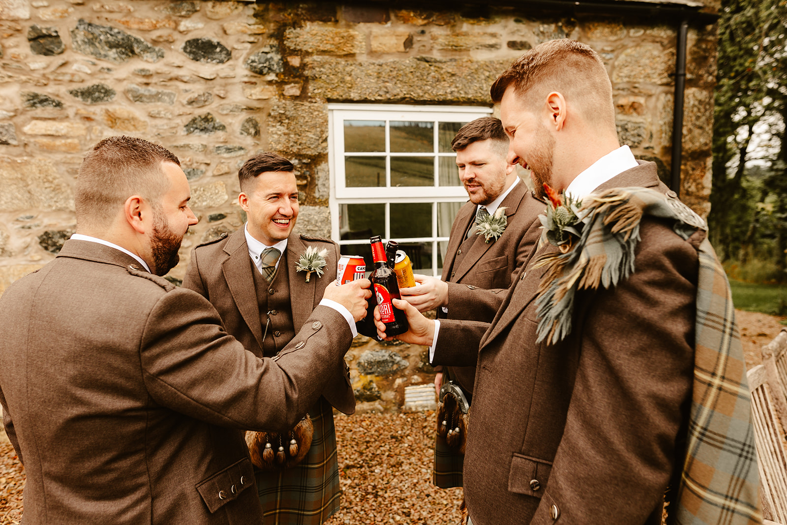 groomsmen cheers their drinks together outdoors during a Scottish wedding ceremony at Aswanley